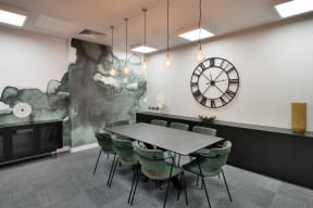 a dining room with a table and chairs and a clock on the wall