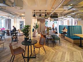 A modern office space with wooden floors and a variety of seating options.