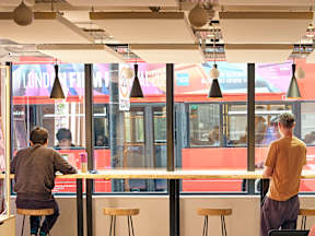 Two men are sitting at a counter in a brightly lit restaurant.