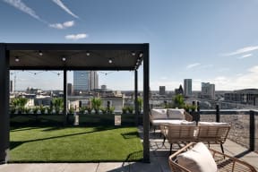 a view of the city from a roof top terrace with chairs and grass