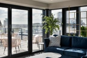 a living room with a blue couch and a balcony with a city view