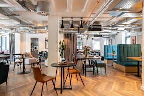 A modern dining area with wooden floors and a variety of chairs and tables.