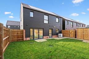 A modern house with a grey exterior and a green lawn in front at The Woodlands Apartments, Milton Keynes