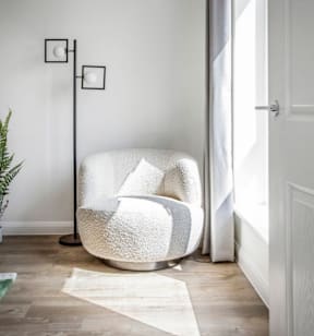 A white chair with a fluffy texture is placed in a room with a white door and a white wall at The Foundry Apartments, Bordon