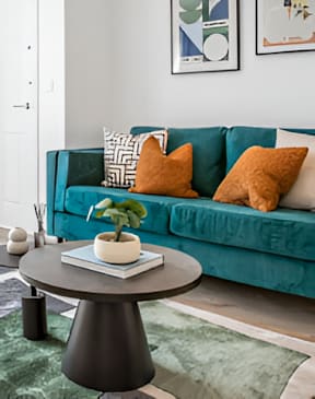 A living room with a blue couch and a round table with a plant on it at The Foundry Apartments, Bordon