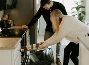 A man and a woman are cooking in a modern kitchen at The Foundry Apartments, Bordon, GU35 9FE