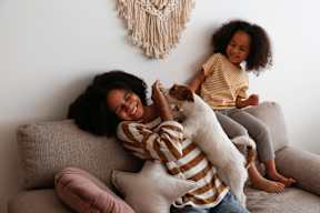 A woman is sitting on a couch with a child and a dog at The Foundry Apartments, Bordon, GU35 9FE