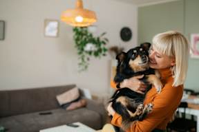 A woman is holding a dog in her arms at The Woodlands Apartments, Milton Keynes, MK5 6GS