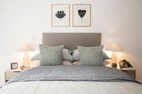 A bed with a grey headboard and two grey pillows is in the image.