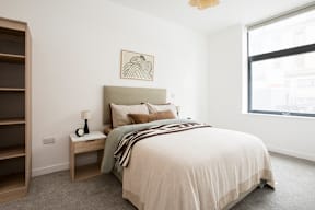 A bedroom with a large bed and a nightstand with a lamp.