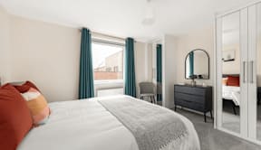 A bedroom with a large bed, a dresser, and a mirror at Origins Apartments, Cambridge, CB3 0UX