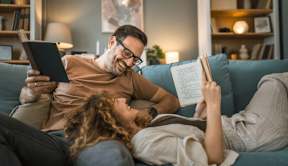 A man and a woman are reading books on a couch at Origins Apartments, Cambridge