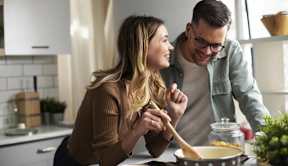 A man and a woman are cooking together in a kitchen at The Woodlands Apartments, Milton Keynes