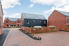A building with a black roof is surrounded by a brick wall at The Woodlands Apartments, Milton Keynes, MK5 6GS