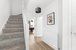 A hallway with a staircase and a framed picture on the wall at The Woodlands Apartments, Milton Keynes, MK5 6GS