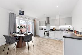 A modern kitchen with a dining table set for two at The Woodlands Apartments, Milton Keynes