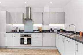 A modern kitchen with white cabinets and a stainless steel range hood at The Woodlands Apartments, Milton Keynes, MK5 6GS