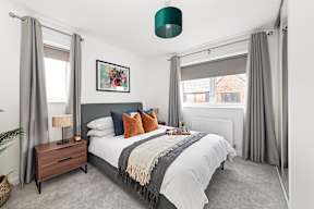 A bedroom with a large bed, a nightstand with a lamp, and a framed picture on the wall at The Woodlands Apartments, Milton Keynes
