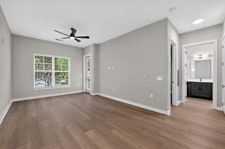A room with a ceiling fan and wooden flooring.