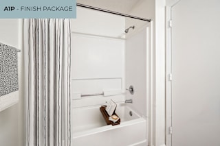 A white bathroom with a striped shower curtain and a white bathtub