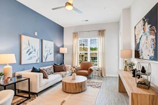 A living room with a white couch, a coffee table, and a painting on the wall.