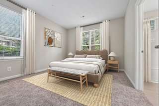 A bedroom with a large bed and a window with curtains.