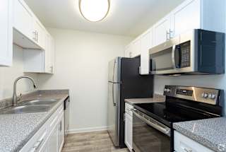 a kitchen with white cabinets and black appliances  at St. Andrews Reserve, North Carolina