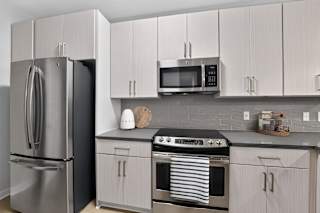 A modern kitchen with a stainless steel refrigerator, microwave, and oven.