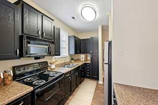 A kitchen with black cabinets and a black stove top oven.