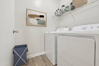 A laundry room with a washer and dryer and a painting on the wall.