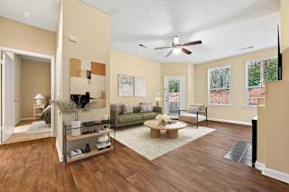 A living room with a brown floor and a ceiling fan.