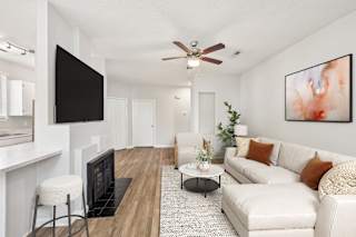 A living room with a white couch and a black television.