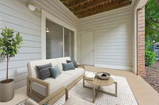 A white couch with blue pillows sits on a patio with a coffee table.