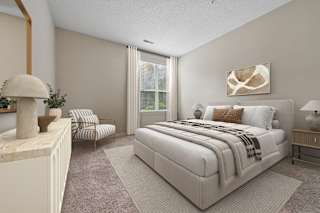 A bedroom with a large bed and a chair.
