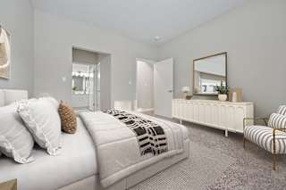 A bedroom with a bed, a chair, and a mirror.