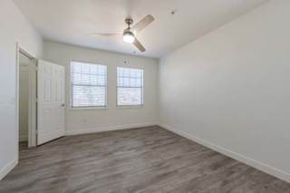 A room with a ceiling fan and two windows.