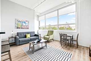 a living room with a couch and a table with a chair and a large window