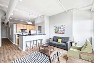 a living area with a couch coffee table and chairs and a kitchen with a breakfast bar