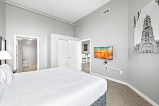 a bedroom with a large white bed and a tv on the wall