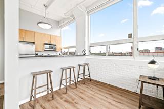 a kitchen with a bar and stools in front of a large window