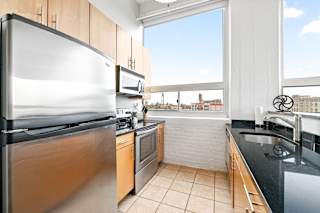 a kitchen with black countertops and stainless steel appliances and a large window