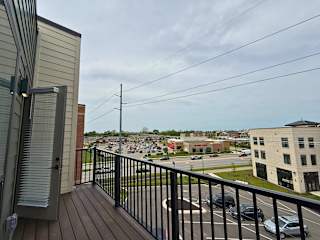 A view from a balcony overlooking a parking lot and buildings.