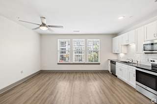 A spacious kitchen with white cabinets and a wooden floor.