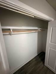 A white closet with a door and a shelf.