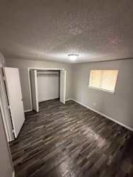A room with wooden flooring and a window with blinds.