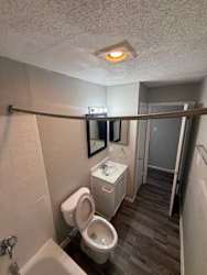 A bathroom with a toilet, sink, and mirror.