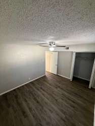 A room with a ceiling fan and light fixture, and a door on the right.