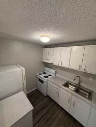 A small white kitchen with a sink, stove, and refrigerator.