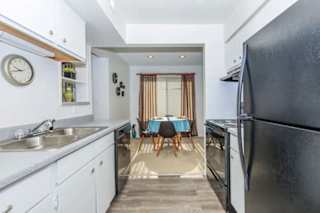 A kitchen with a black refrigerator and a dining table with chairs.