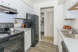 A kitchen with black appliances and white cabinets.